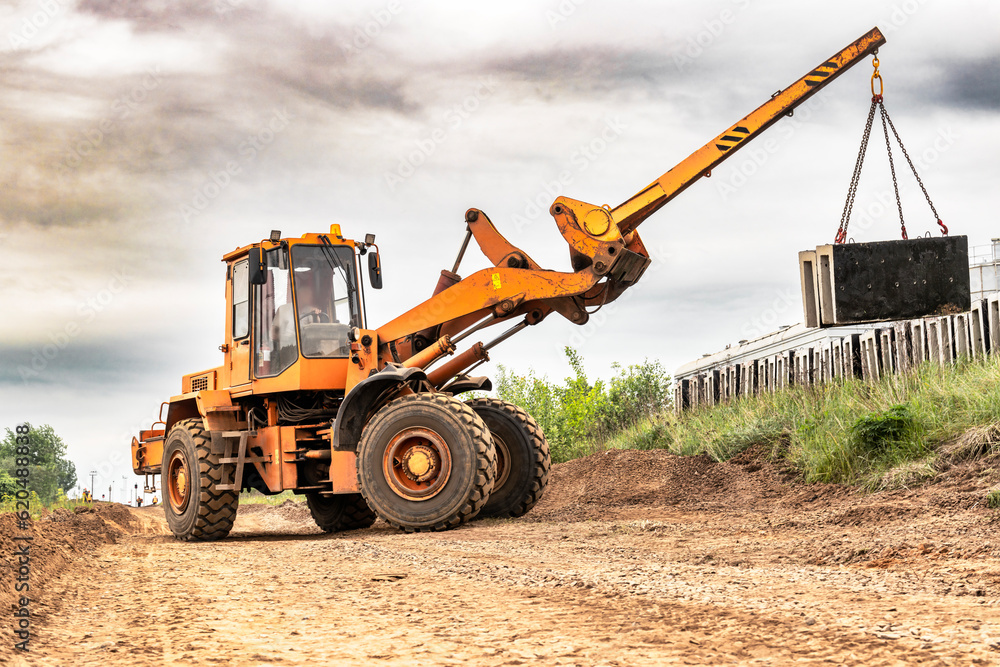 Powerful wheel loader for transporting bulky goods on the construction site. Transportation of concrete products. Transportation and movement of heavy long cargoes. Powerful wheel loader for transporting bulky goods on the construction site. Transportation of concrete products. Transportation and movement of heavy long cargoes.