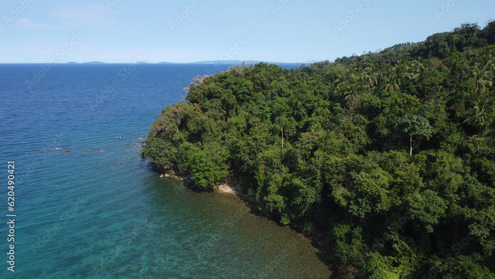 Aerial view of the coast of the island and the sea. The shore of a tropical island covered with tropical rainforest.
