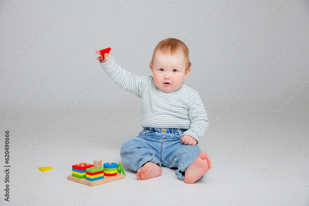 charming baby in a T-shirt and jeans is playing with toys, a postcard, a banner, a place for text. High quality photo. baby boy playing a logical educational game charming baby in a T-shirt and jeans is playing with toys, a postcard, a banner, a place for text. High quality photo. baby boy playing a logical educational game