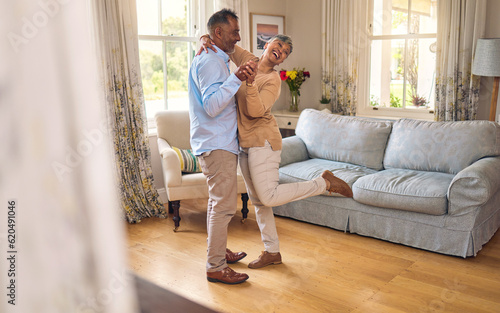 Love, funny and dance with a senior couple in the living room of their home together for bonding. Marriage, retirement or romance with an elderly man and woman laughing in the lounge of their house