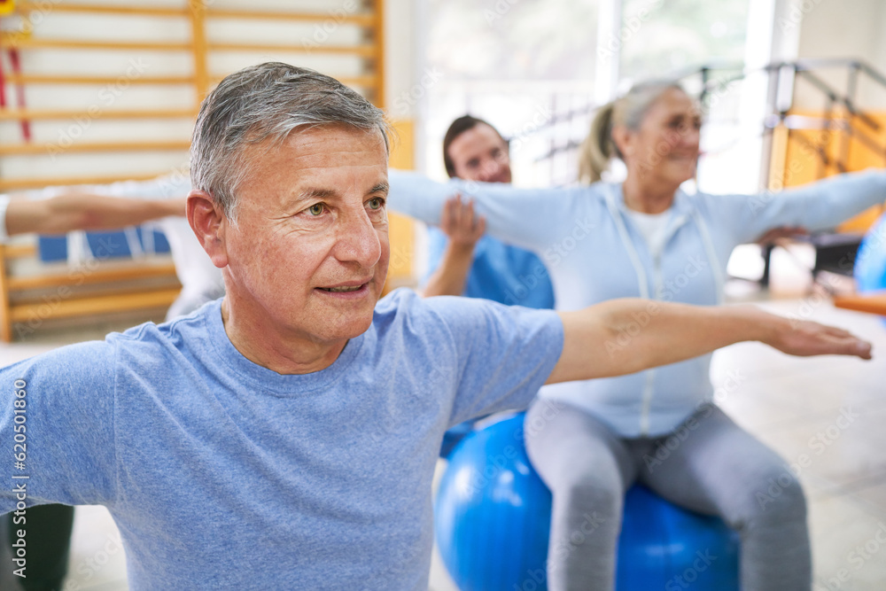 Elderly people exercising on fitness ball during exercise class Elderly people exercising on fitness ball during exercise class