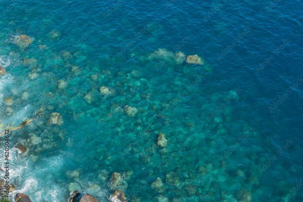 Drone view of rocks and blue pristine sea with clear transparent water. Ocean background with copy space