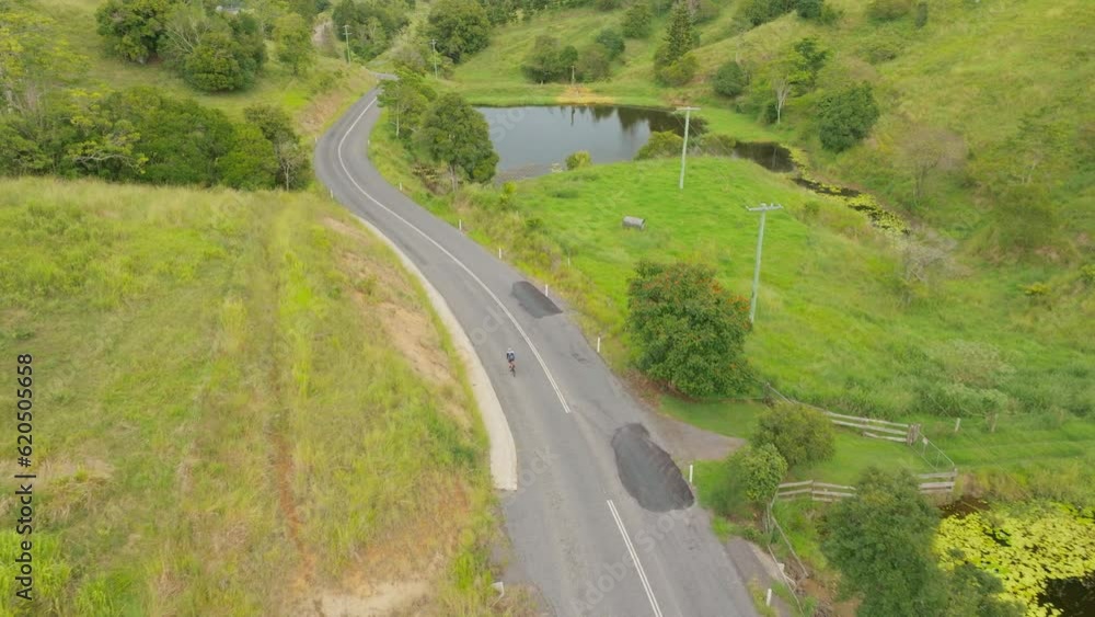 Athletic Cyclist Riding Bike Down Scenic Bush Rural Australian Road, 4K Drone Slow Motion