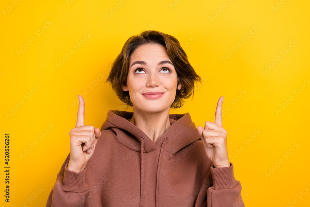 Portrait young girl show shopping center store poster up empty space wear brown hood shirt isolated yellow color background Portrait young girl show shopping center store poster up empty space wear brown hood shirt isolated yellow color background