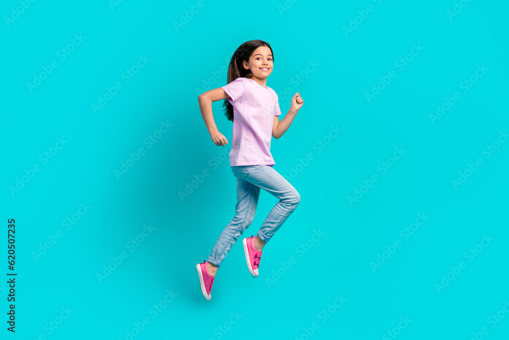 Full body photo of small girl run fast speed have fun wear pink t-shirt jeans hurry after school isolated on aquamarine color background Full body photo of small girl run fast speed have fun wear pink t-shirt jeans hurry after school isolated on aquamarine color background