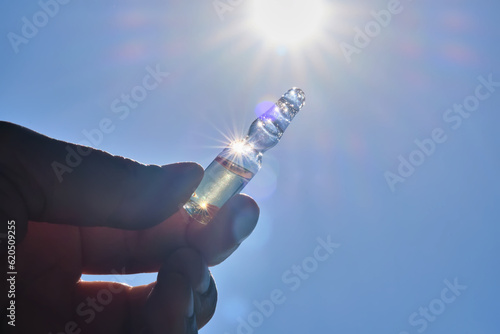 Ampoule in hand against the blue sky.