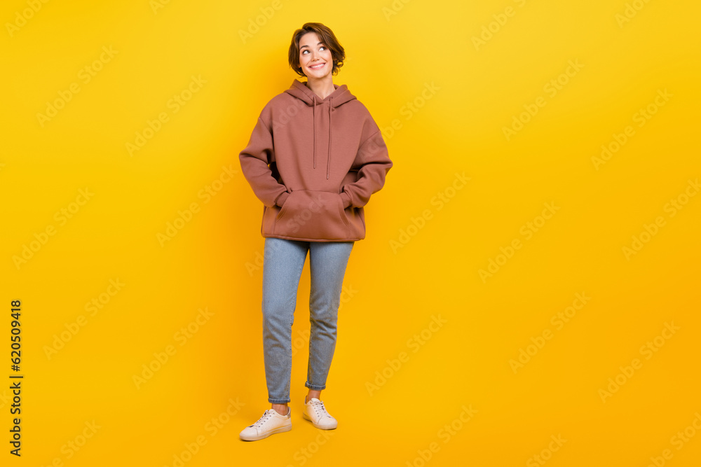 Full length size cadre of dreaming lovely woman wear brown hoodie hands pockets denim jeans look mockup isolated on yellow color background Full length size cadre of dreaming lovely woman wear brown hoodie hands pockets denim jeans look mockup isolated on yellow color background