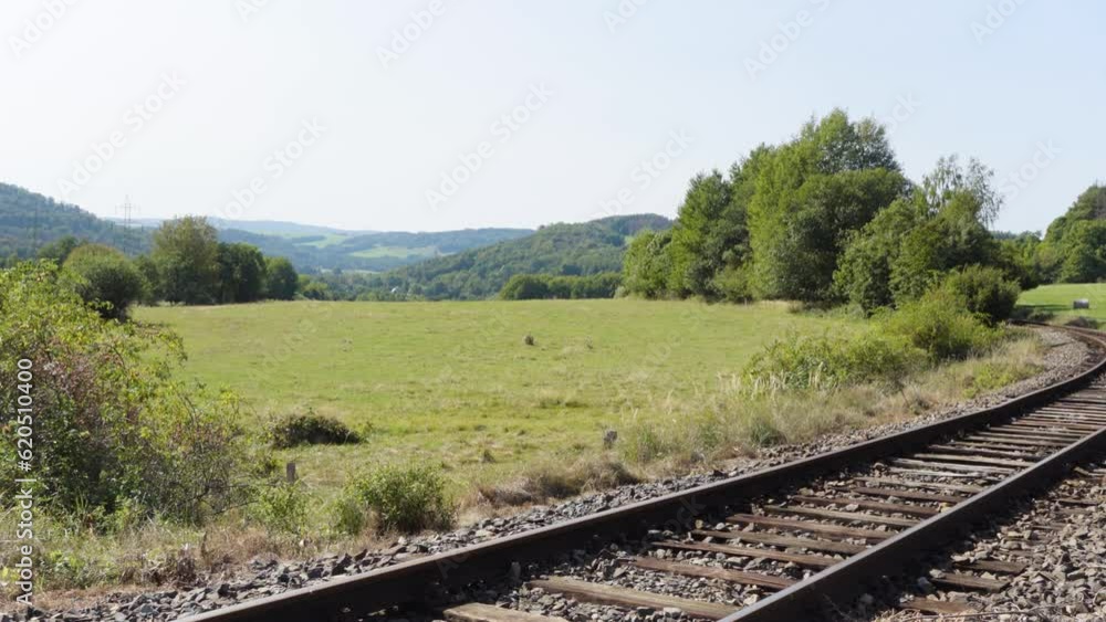 A train track curves through a countryside on a sunny day A train track curves through a countryside on a sunny day
