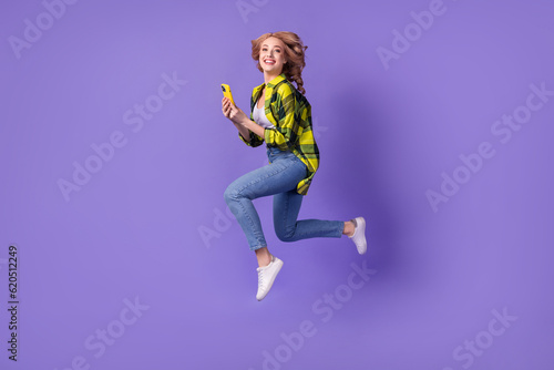Full body cadre of running funky young woman running with smartphone favorite app shopping store online isolated on purple color background