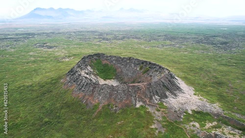 aerial volcano eldborg, push out movement, green summer hazy misty volcanic landscape, shrub spatter cone, touristic trail for outdoor travellers. cinematic drone shot, epic travel destination. photo