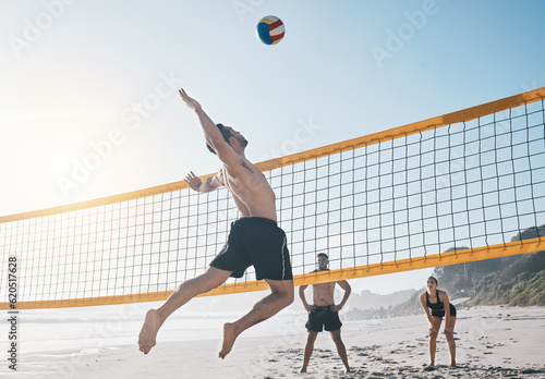 Man, jump and volleyball in air on beach by net in sports match, game or competition. Body of male person jumping for ball in volley or spike in healthy fitness, energy or exercise by the ocean coast photo
