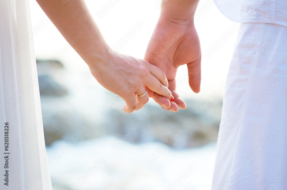 Fototapeta premium Love - romantic couple holding hands on a beach in sunset.