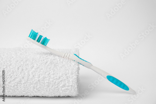 Light blue toothbrush and terry towel on white background