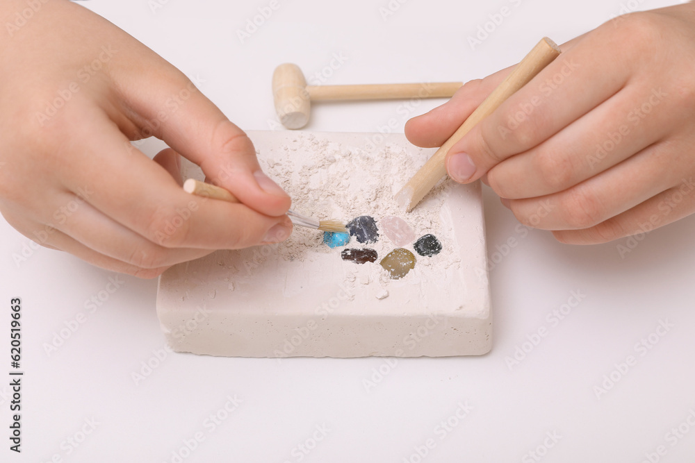 Child playing with Excavation kit at white table, closeup. Educational toy for motor skills Child playing with Excavation kit at white table, closeup. Educational toy for motor skills