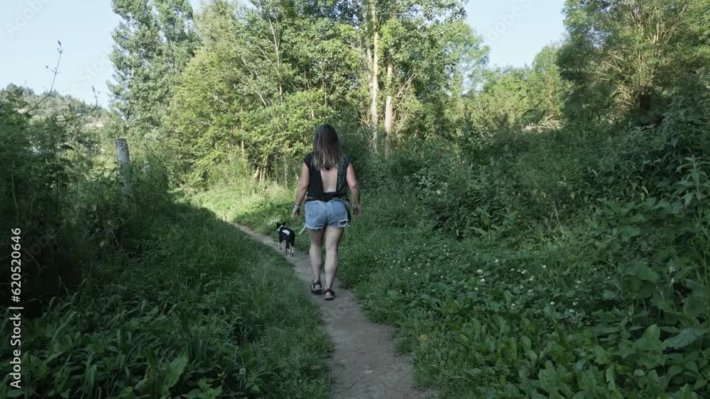 Woman and her dog taking a walk along a narrow path in the countryside Woman and her dog taking a walk along a narrow path in the countryside