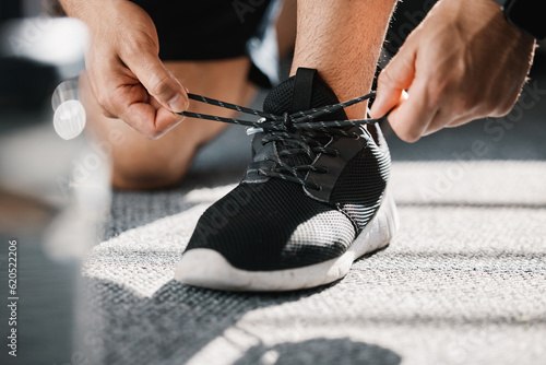 Exercise, shoes and tie laces with a man in a sports gym getting ready for a cardio or endurance workout. Fitness, running and preparation with a male athlete or runner at the start of training