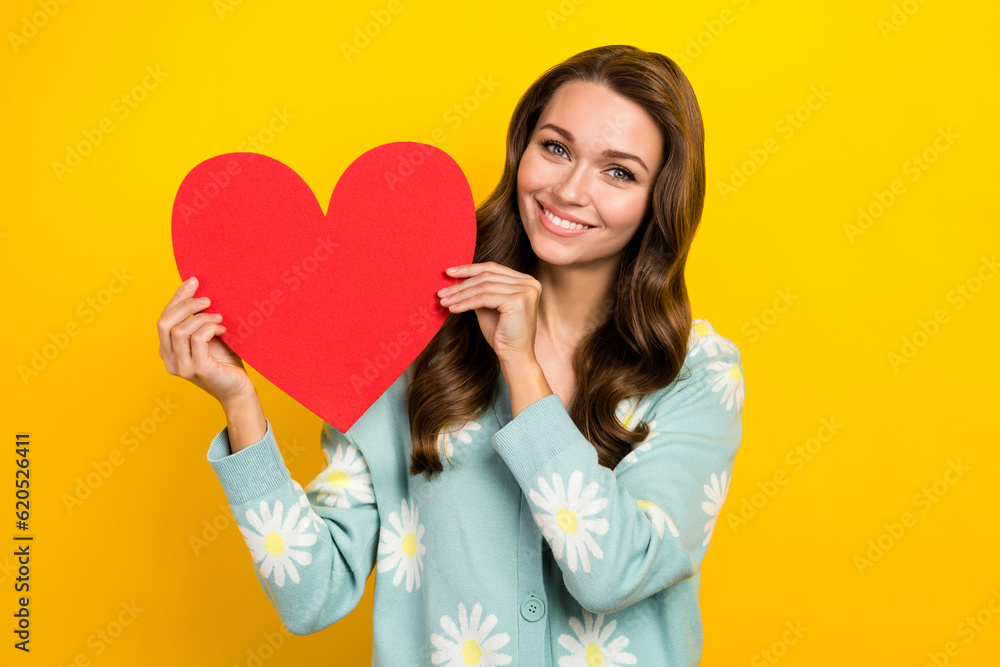 Portrait of smiling attractive lady curly hairstyle hold paper heart shape postcard international woman day gift isolated on yellow color background Portrait of smiling attractive lady curly hairstyle hold paper heart shape postcard international woman day gift isolated on yellow color background