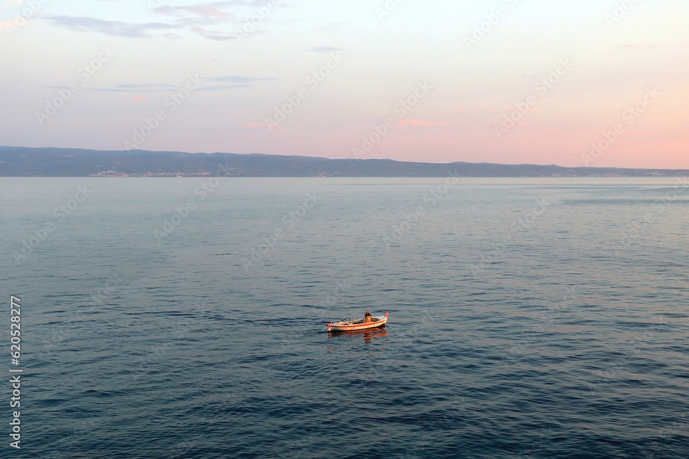 Beautiful sunset over the Adriatic Sea. Small old fashioned fishing boat at the sea.