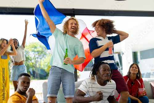 Group of diverse friends sitting on sofa  watching sport on tv and cheering