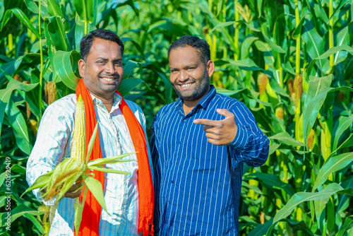 young indian farmer showing corn at corn field.