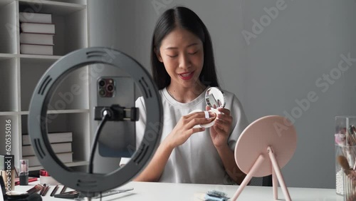 beautiful young woman influencer review makeup face by applying sponge on faical looking at the mirror, beauty blogger concept. photo