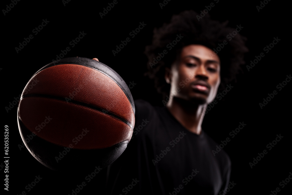 Basketball player holding a ball at camera. Shallow focus. Young african american sports man against black background. Basketball player holding a ball at camera. Shallow focus. Young african american sports man against black background.