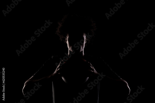 Basketball player silhouette holding a ball against black background. Side lit american man.