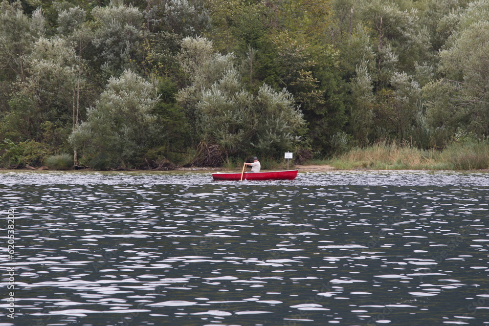 Fototapeta premium Photo of a man peacefully rowing a small boat on a lake, Austria