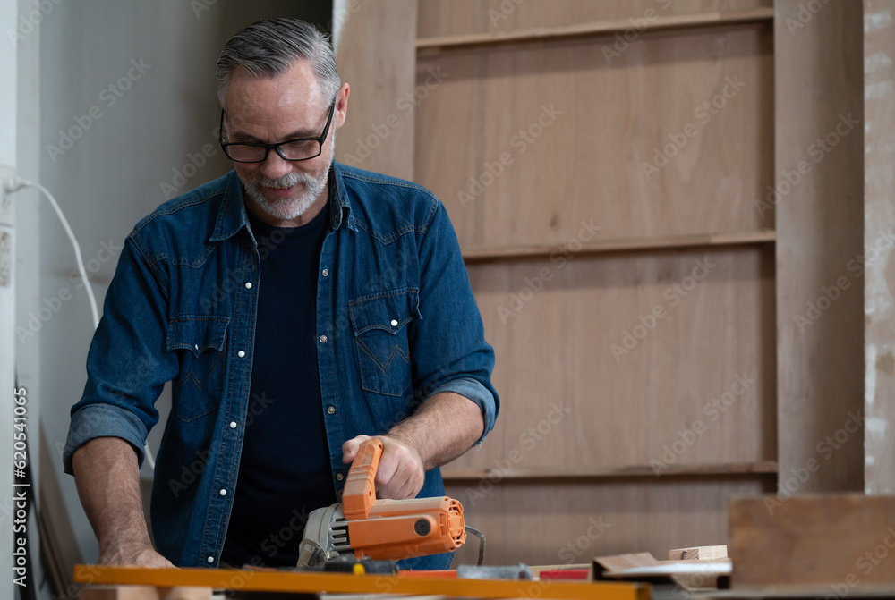 Bearded man carpenter working with skill in carpentry workshop. Professional joiner works with tools in woodworking. Portrait of mature woodworker making or repairing furniture. Craftmanship industry Bearded man carpenter working with skill in carpentry workshop. Professional joiner works with tools in woodworking. Portrait of mature woodworker making or repairing furniture. Craftmanship industry
