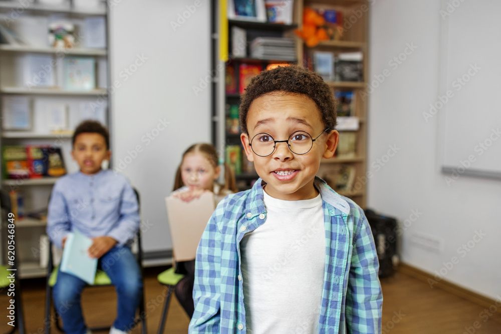 Schoolboy standing in middle of classroom and answering question in front of classmates and teacher. Schoolboy standing in middle of classroom and answering question in front of classmates and teacher.