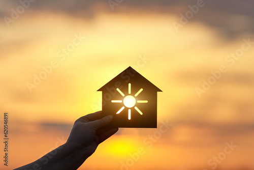 Hand holds a wooden house in the form of a sun