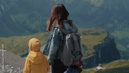 Rear view of mother with two kids, boy and girl, hiking and enjoying picturesque view of mointains lake photo