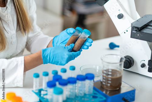 Scientist carefully handles fecal transplant liquid in test tubes within the lab, exploring the potential of innovative medical procedure and its impact on gastrointestinal health