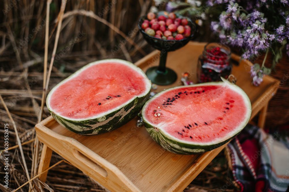 Sliced juicy watermelon on a wooden tray in nature. Picnic in nature. Sliced juicy watermelon on a wooden tray in nature. Picnic in nature.