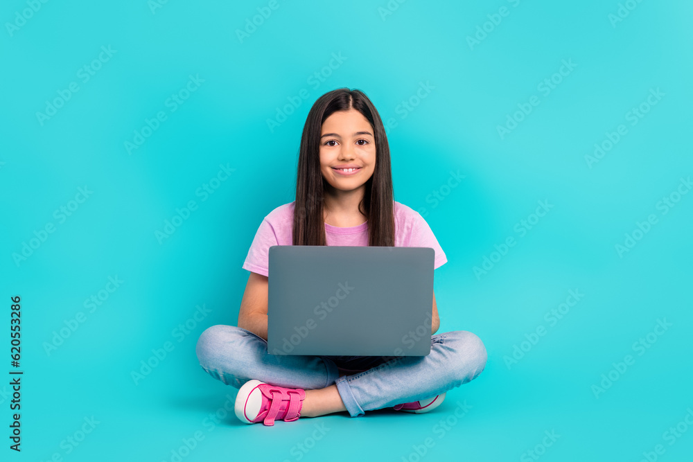 Naklejka premium Full body size photo of cheerful preteen girl writing essay computer netbook education literature isolated on aquamarine color background