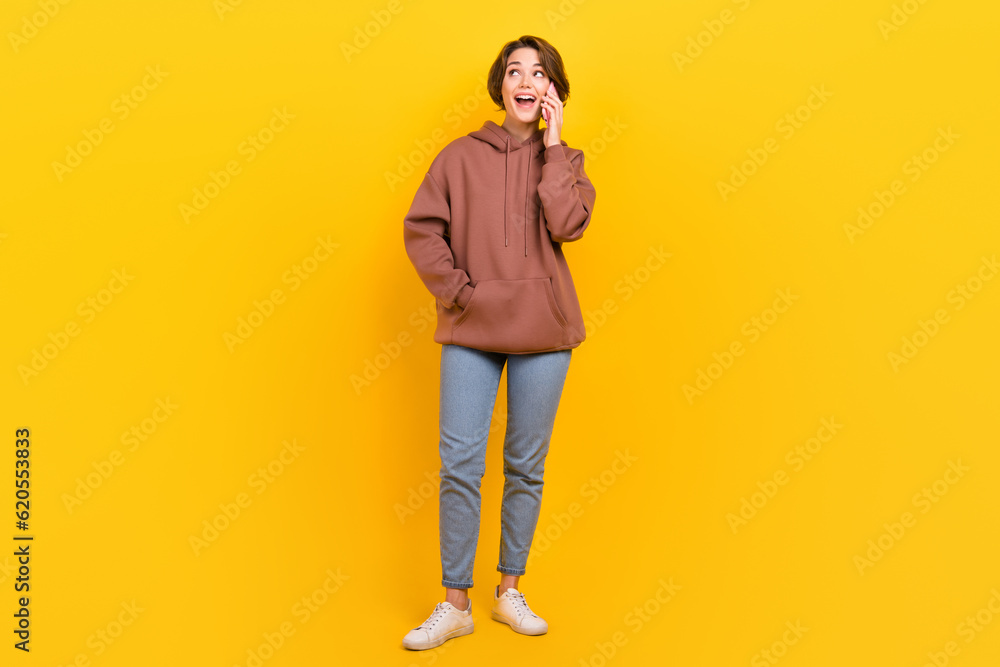 Full length photo of lovely cheerful person talk communicate telephone good mood isolated on yellow color background Full length photo of lovely cheerful person talk communicate telephone good mood isolated on yellow color background