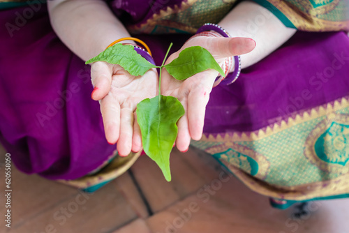 Photography devotee holding holy Aegle marmelos or Bael leaf in hand from different angle at