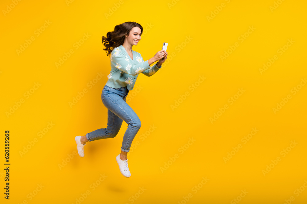 Full length body photo of young good mood run fast speed girl blogger wavy brown hairdo recording phone new video isolated on yellow color background