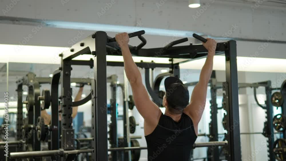 Fit Adult Man Doing Pullups in Gym. Muscular Athlete Practicing Pullup in Sport Gym. Athlete Performing Pullup Workout. Unrecognizable Ambitious Male Sportsman in Black Training Wear Working Out Back Fit Adult Man Doing Pullups in Gym. Muscular Athlete Practicing Pullup in Sport Gym. Athlete Performing Pullup Workout. Unrecognizable Ambitious Male Sportsman in Black Training Wear Working Out Back