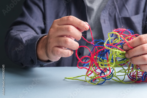 Closeup man try to fix the problem of tangled ropes, psychotherapy concept, complicated problem