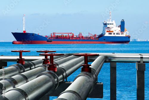Ship near LNG terminal. Pipes on seashore. Pipeline for supply of liquefied gas. Ship sail to harbor. Transportation of LNG gas. Fuel pipes for refueling ships. Sea ship sails to port
