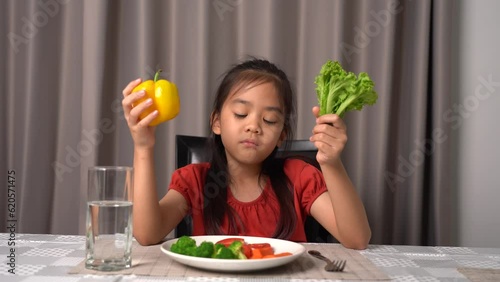Little cute kid girl refusing to eat healthy vegetables. Children do not like to eat vegetables.