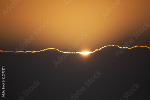Close image of sunset sun rising over clouds. 