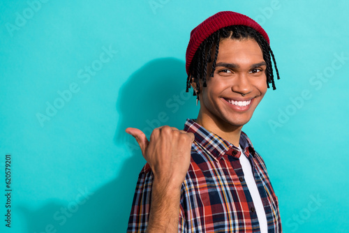 Photo of positive optimistic guy with dreadlocks wear plaid shirt indicating at sale empty space isolated on turquoise color background