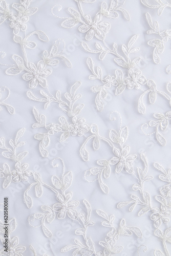 Vertical look of chic embroidered white satin fabric. flowers embroidered with beads and sequins. Wedding festive background