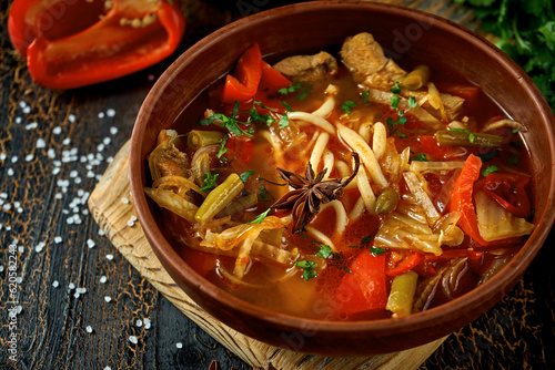 Georgian Laghman soup with ribs and noodles in a clay pot. Dark background