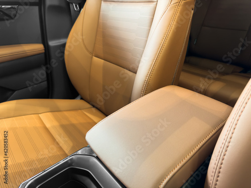 Modern luxury car brown leather interior. Part of orange leather car seat details with white stitching. Interior of prestige car. Comfortable perforated leather seats. Perforated leather. © Aleksei