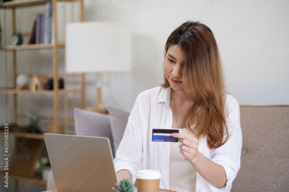 Woman shopping on laptop holding credit card for Internet online e-commerce shopping spending money Online shopping Mobile phone laptop technology concept Woman shopping on laptop holding credit card for Internet online e-commerce shopping spending money Online shopping Mobile phone laptop technology concept