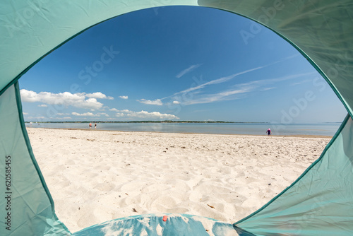 Fototapeta Naklejka Na Ścianę i Meble -  View from inside a tent onto beautiful white sand beach at the Baltic Sea at the Flensburger Förde in North Germany