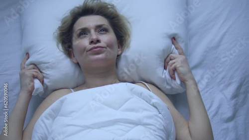 Unhappy woman can't fall asleep because of headache, suffering migraine and hot flushes at night, bad sleeping conditions, stuffiness, menopause symptom
